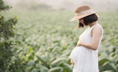 Uma jovem grávida toca alegremente na sua barriga enquanto passeia na natureza. Uma jovem grávida toca alegremente na sua barriga enquanto passeia na natureza.
