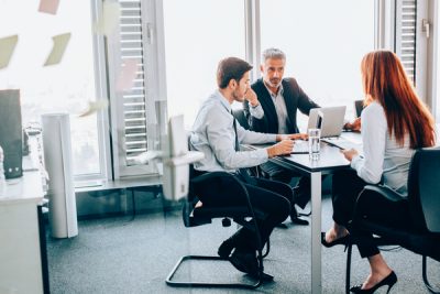 Ilustre o conceito de gestão empresarial mostrando três pessoas a terem uma reunião de negócios num escritório. Três pessoas numa reunião de negócios num escritório.