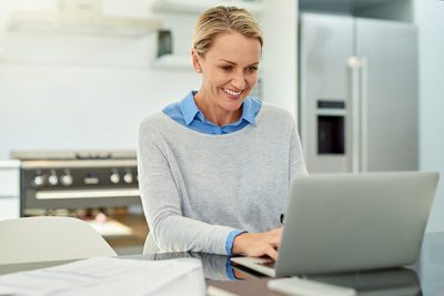 Mulher sorridente navegando na Internet em seu laptop.