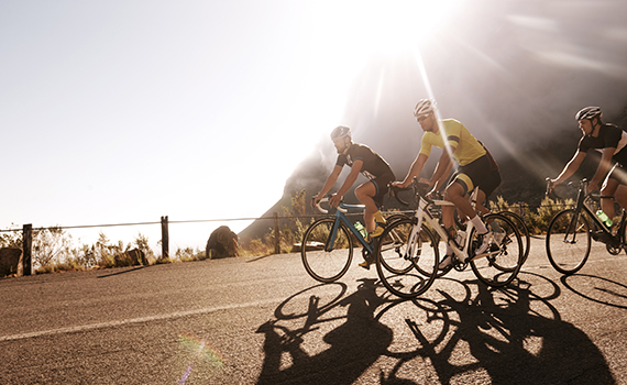 Três jovens ciclistas treinam para a Volta à França. 
