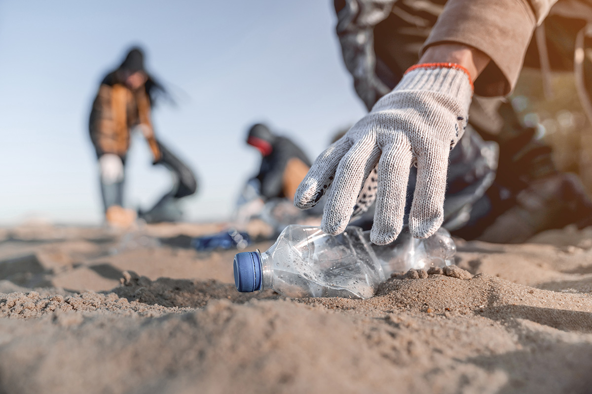 Voluntário recolhe lixo na praia. 