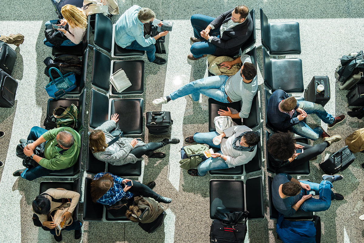Vista aérea de uma área de espera de aeroporto. Passageiros esperando para pegar seus voos.