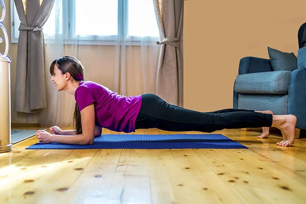 Uma mulher adulta a fazer exercício excêntrico em casa para melhorar a sua saúde física e mental. 