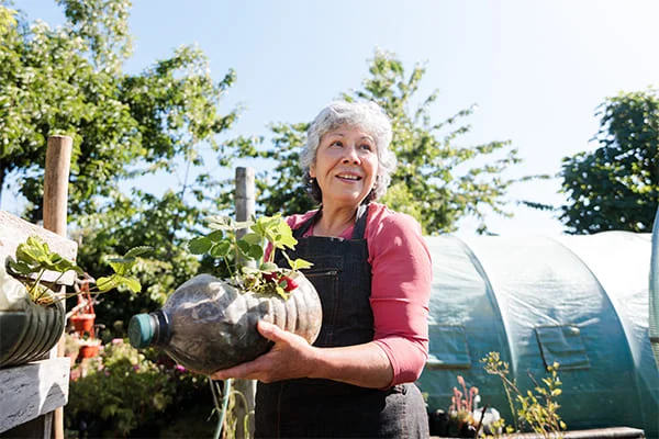 Uma idosa cuidando das suas plantas para melhorar a sua saúde física e emocional.