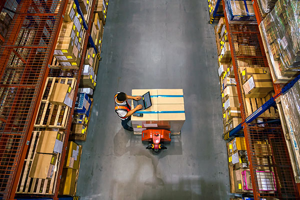 top-view-of-warehouse-worker-using-laptop-to-check-location-of-goods-
