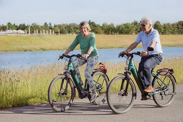 Dois idosos a andar de bicicleta para diminuir o risco de desenvolver demência.
