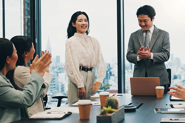 Stakeholders - Um grupo de funcionários de uma empresa aplaude os méritos de uma colega.