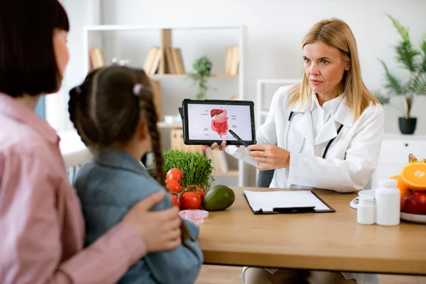 Médica explicando como funciona a microbiota intestinal a uma menina.