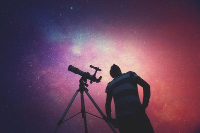 man-looking-at-the-stars-with-telescope-beside-him-