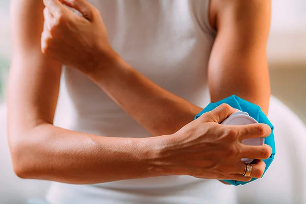 Uma atleta segurando uma bolsa de gelo para a recuperação muscular do braço.