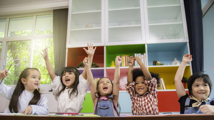 Ilustrar cómo los niños demuestran sus emociones en un aula de clase Grupo de niños sonriendo y levantando los brazos dentro de un salón de clases