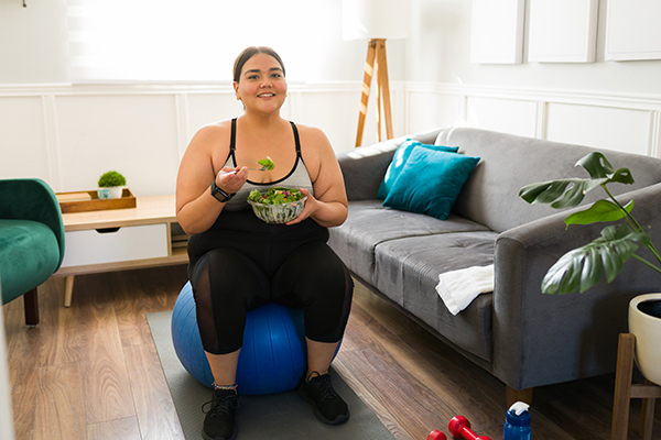 Una mujer con sobrepeso come una ensalada después de entrenar. Una mujer con sobrepeso come una ensalada después de entrenar.