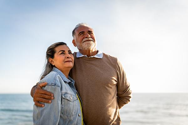 Una pareja de adultos mayores saludables paseando en la playa.
