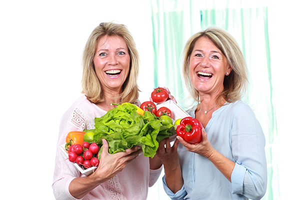 Dos mujeres adultas sosteniendo verduras en sus manos muy felizmente. Dos mujeres adultas sosteniendo verduras en sus manos muy felizmente.