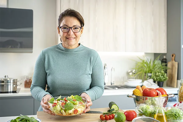 Una señora sosteniendo un bol de ensalada en sus manos. Una señora sosteniendo un bol de ensalada en sus manos.