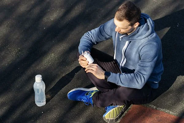 Un deportista sosteniendo un frasco de medicamento en sus manos. Un deportista sosteniendo un frasco de medicamento en sus manos.